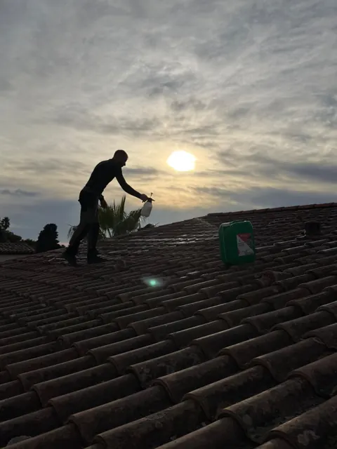 Couvreur au travail sur une toiture en tuiles