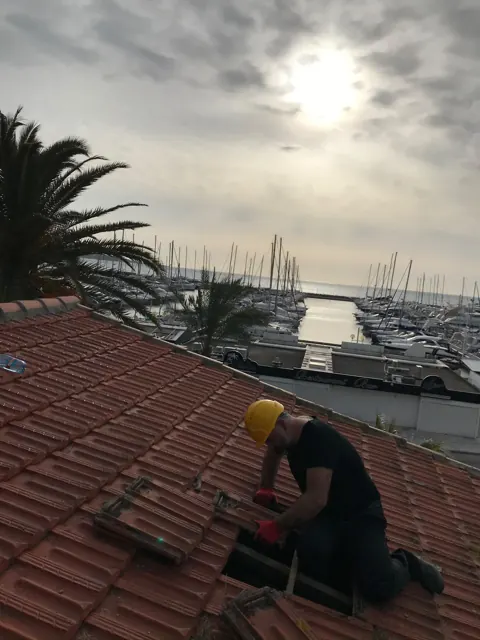 Couvreur au travail sur une toiture en tuiles
